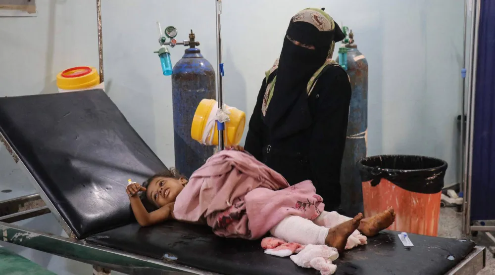 أم يمنية في مستشفى رفقة طفلتها المصابة جراء هجوم حوثي (أ.ف.ب)