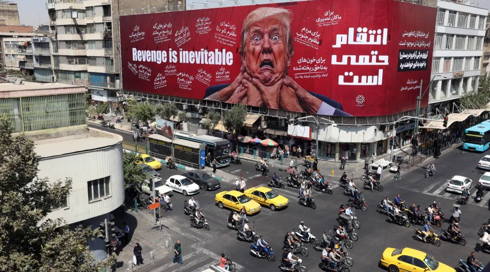 إيرانيون يقودون سياراتهم بالقرب من لوحة إعلانية مناهضة لترمب في طهران (إ.ب.أ)