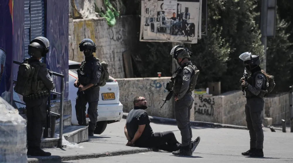 رجل فلسطيني مكبل اليدين يُحتجز من قبل ضباط شرطة الحدود الإسرائيلية خلال عملية للجيش في مخيم قلنديا للاجئين في الضفة الغربية (أ.ب)