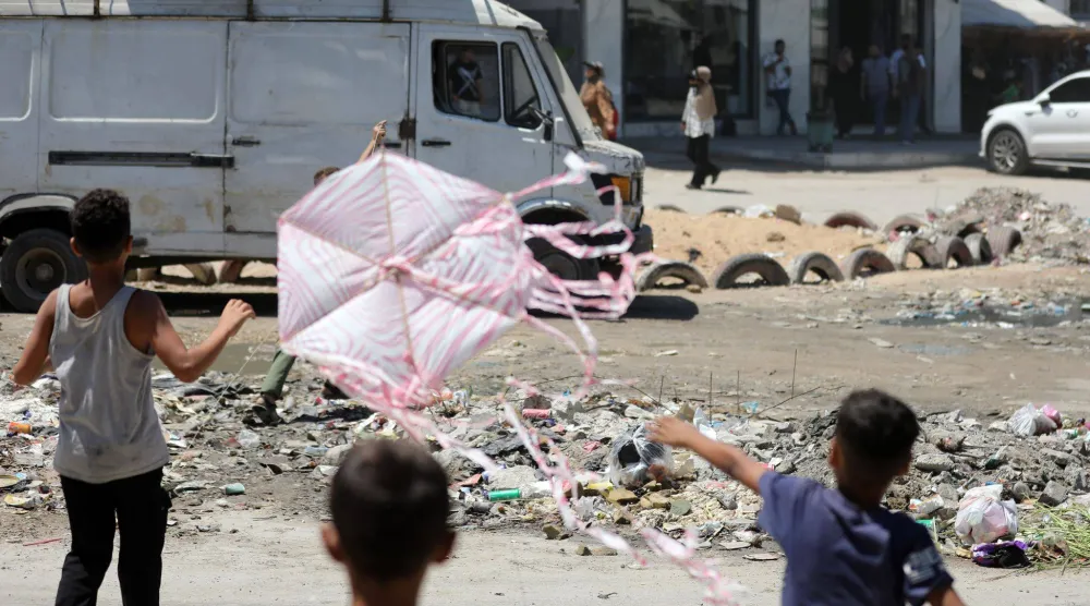 أطفال فلسطينيون يصنعون الطائرات الورقية ويطلقونها في غزة (د.ب.أ)
