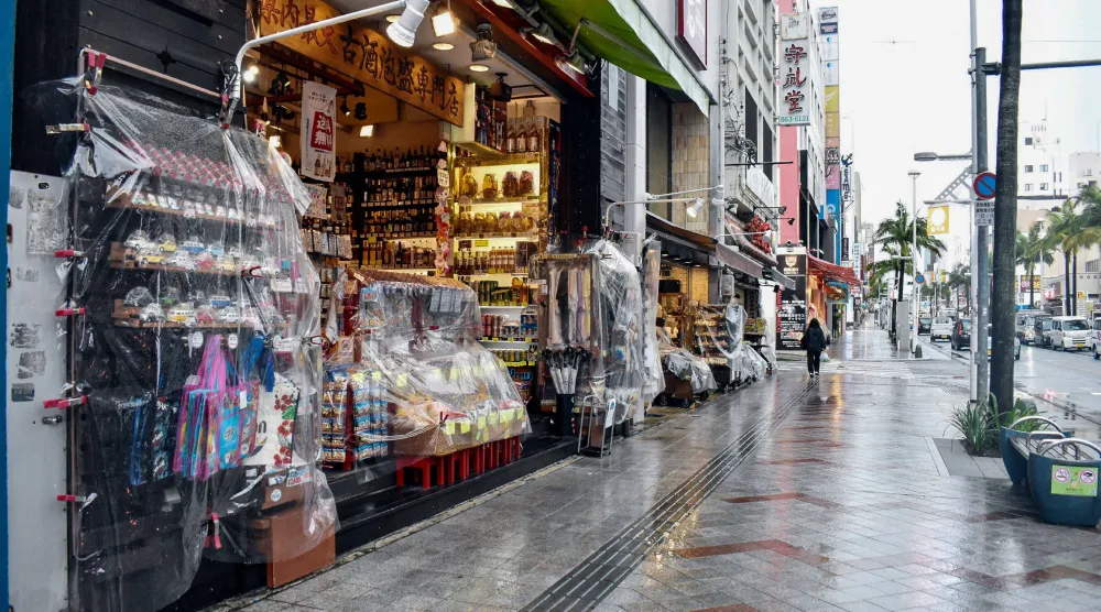 Shops cover their merchandise in plastic to protect it from the rain as Typhoon Saudel passes in Naha on August 26, 2026. (AFP)