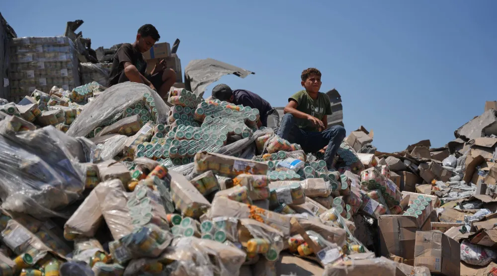فلسطينيون في مستودع للمساعدات الغذائية تضرر من غارة إسرائيلية استهدفت منزلاً مجاوراً في دير البلح وسط غزة الأربعاء (أ.ب)