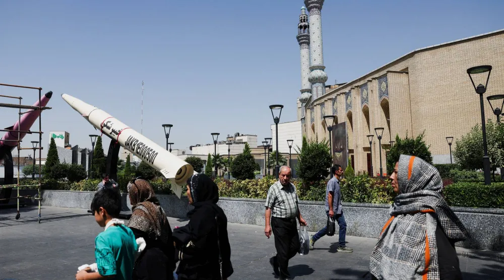 أشخاص يسيرون بجانب مجسم رمزي لصاروخ إيراني بأحد شوارع طهران في مشهد يعكس تصاعد الخطاب العسكري والتعبئة الداخلية بالتزامن مع المفاوضات الجارية حول اتفاق محتمل بين طهران وواشنطن لإنهاء الحرب (رويترز)