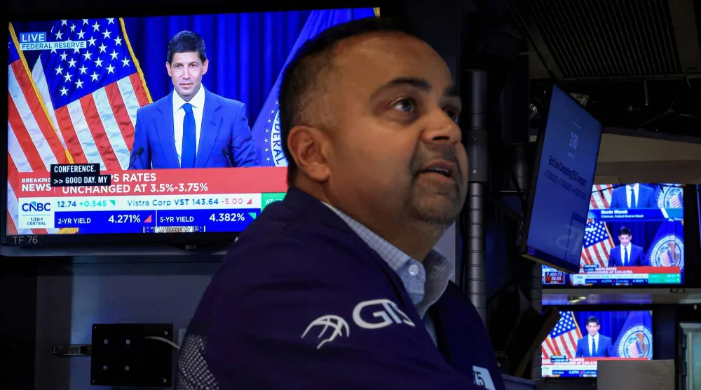 متداول يعمل بينما تبث الشاشات مؤتمراً صحافياً لوارش عقب إعلان سعر الفائدة في يوليو (رويترز)