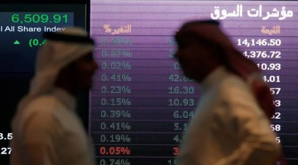 رجلان يتحدثان أمام احد شاشات الأسهم في السوق السعودية (رويترز)
