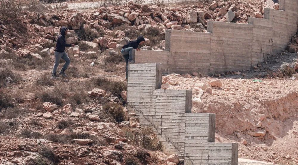 مستوطنون إسرائيليون بالقرب من منزل فلسطيني في قرية قصرة بالضفة الغربية (أ.ف.ب)