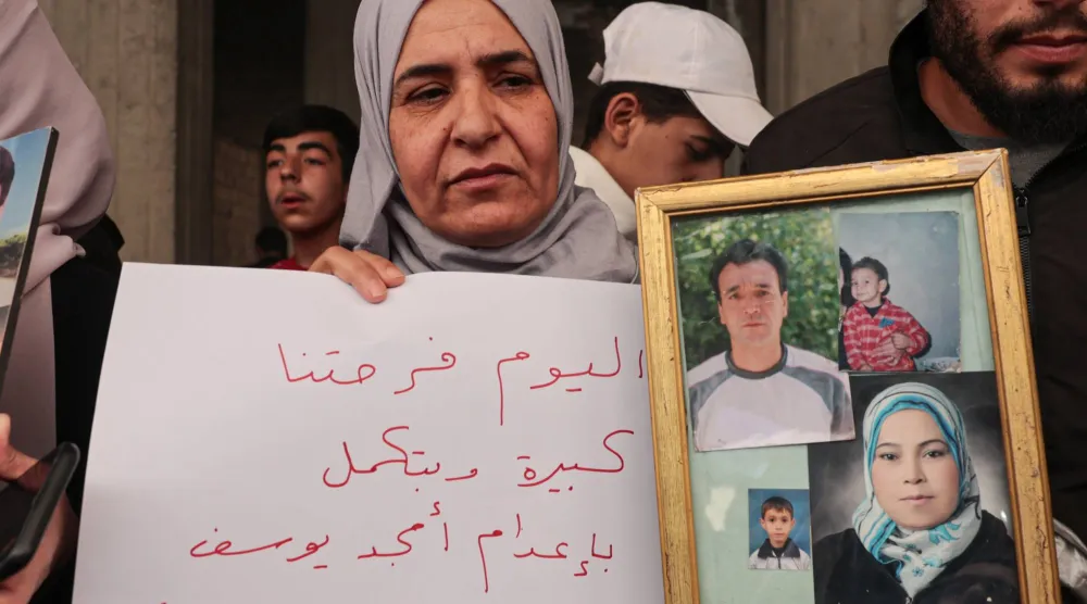 سوريّة تحمل صور أقارب لها قُتلوا في «مجزرة التضامن» بالحي جنوب دمشق 24 أبريل الماضي (إ.ب.أ)