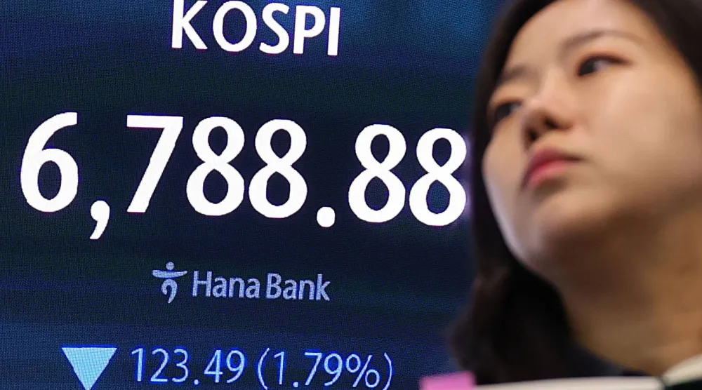 متعاملة تقف أمام شاشة بيانات مالية تعرض مؤشر أسعار الأسهم المركب الكوري (كوسبي) في غرفة تداول بنك هانا في سيول يوم الجمعة (إ.ب.أ)