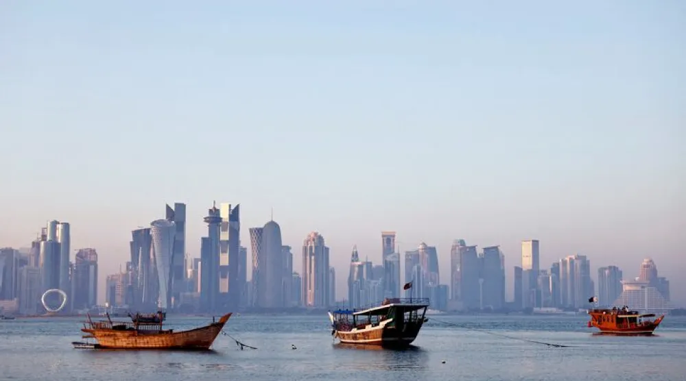 قوارب تُبحر في كورنيش الدوحة بينما يظهر أفق المدينة بالخلفية (رويترز)