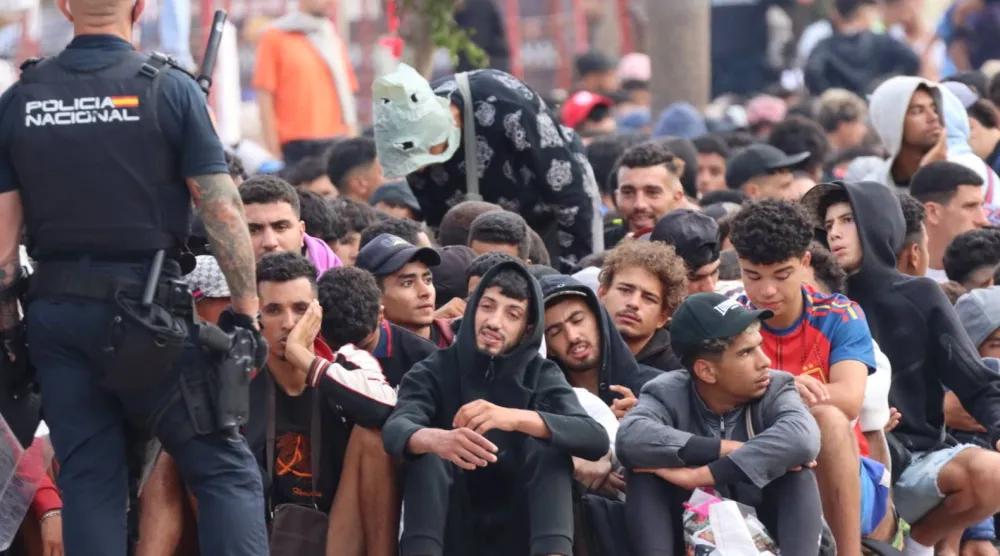 مهاجرون ينتظرون خارج مركز إيواء المهاجرين المؤقت "لوما كولمينار" في سبتة، إسبانيا (إ.ب.أ)