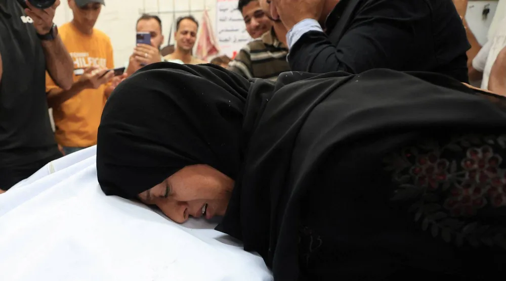 فلسطينيون متأثرون خلال تشييع أحد قتلى الغارات الإسرائيلية في مدينة غزة الاثنين (رويترز)