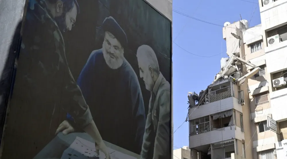 Beyrut’un güney banliyölerinde, Haret Hreik’te İsrail hava saldırısının gerçekleştiği yere yakın bir binada asılı bir pankartta Kasım Süleymani, Hasan Nasrallah ve İmad Muğniye’nin fotoğrafları görülüyor. (Arşiv – EPA)