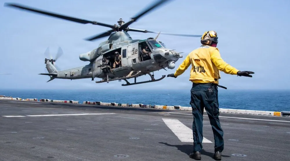 A U.S. sailor directs the takeoff of a helicopter from the deck of the amphibious assault ship USS Boxer while sailing in the Arabian Sea as part of the blockade on Iran (U.S. Navy)