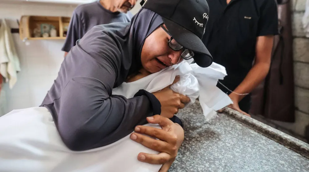 فلسطينية تودع شقيقتها إسراء الحاسي (7 سنوات) بعد أن قُتلت بنيران الجيش الإسرائيلي وسط غزة يوم الثلاثاء (أ.ف.ب)