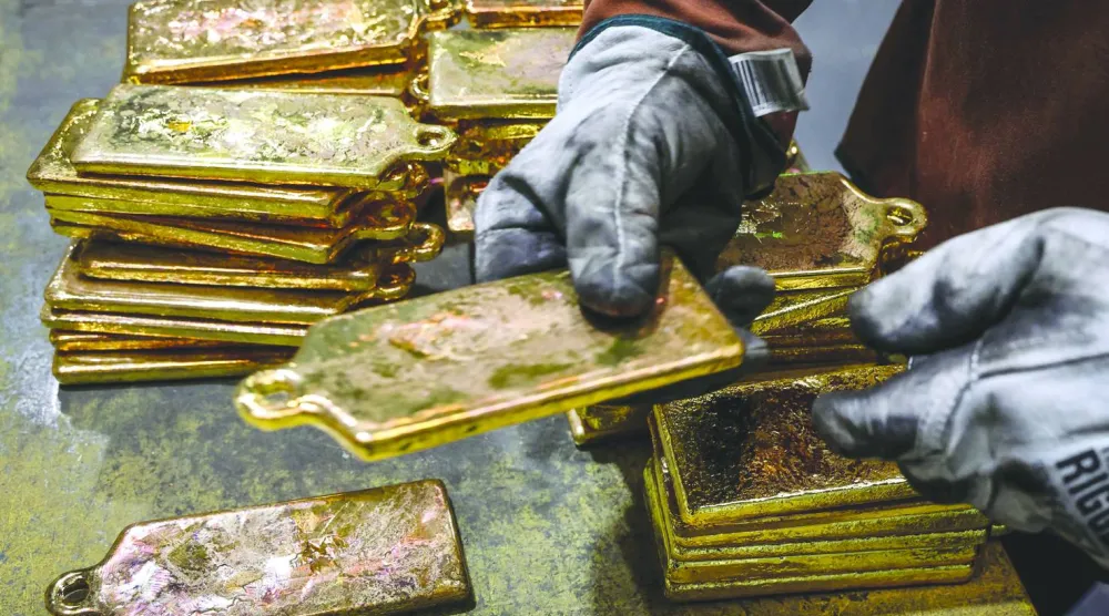 عامل مصفاة يكدّس سبائك الذهب بعد إخراجها من قوالبها في مصهر مصفاة بسيدني (أ.ف.ب)