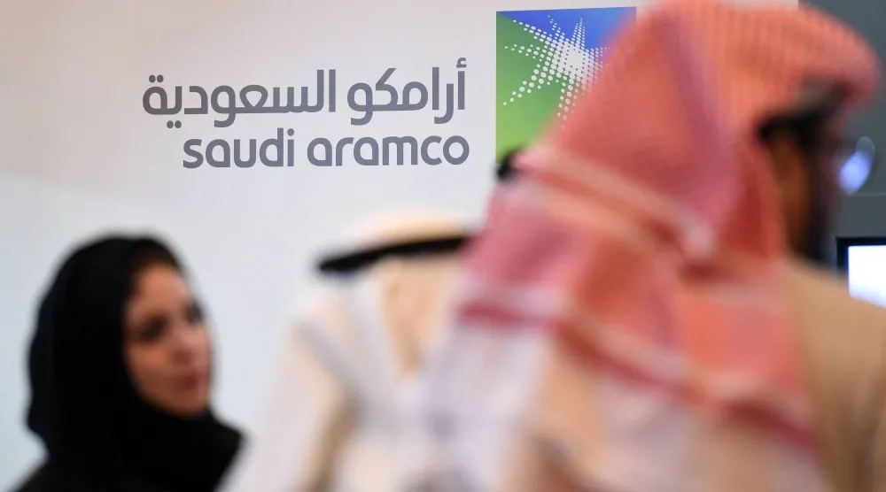 أشخاص يقفون أمام شعار شركة «أرامكو» خلال المنتدى العالمي العاشر للتنافسية (أرشيفية - أ.ف.ب)