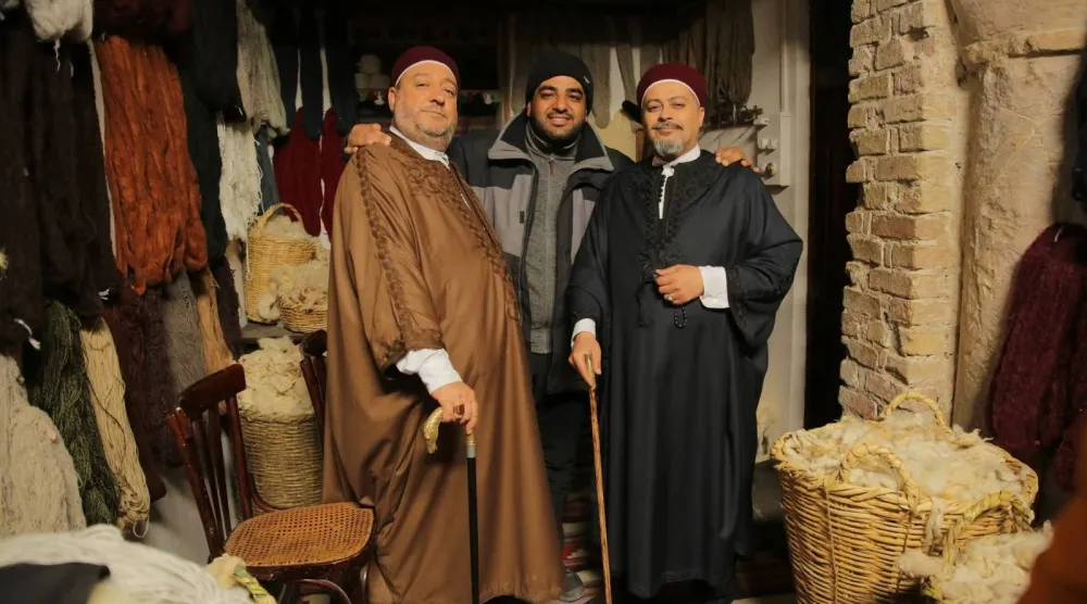 المخرج الليبي أسامة رزق يتوسط الفنانين كافو (إلى اليسار) ومحمد عثمان خلال تصوير مسلسل «زنقة الريح» عام 2019 (الشرق الأوسط)