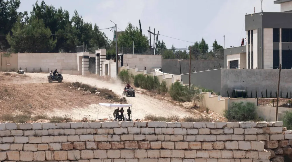 يتجول مستوطنون إسرائيليون بسياراتهم رباعية الدفع بالقرب من منازل الفلسطينيين المحاصرين في قرية قصرة جنوب نابلس بالضفة (أ.ف.ب)