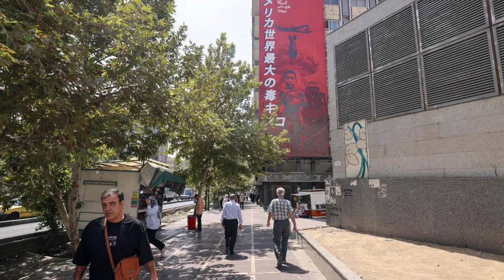 People walk past a large anti-US banner with reference to the dropping of the atomic bomb on the Japanese city of Hiroshima, in Tehran on September 2, 2026. (Photo by Atta KENARE / AFP) / 