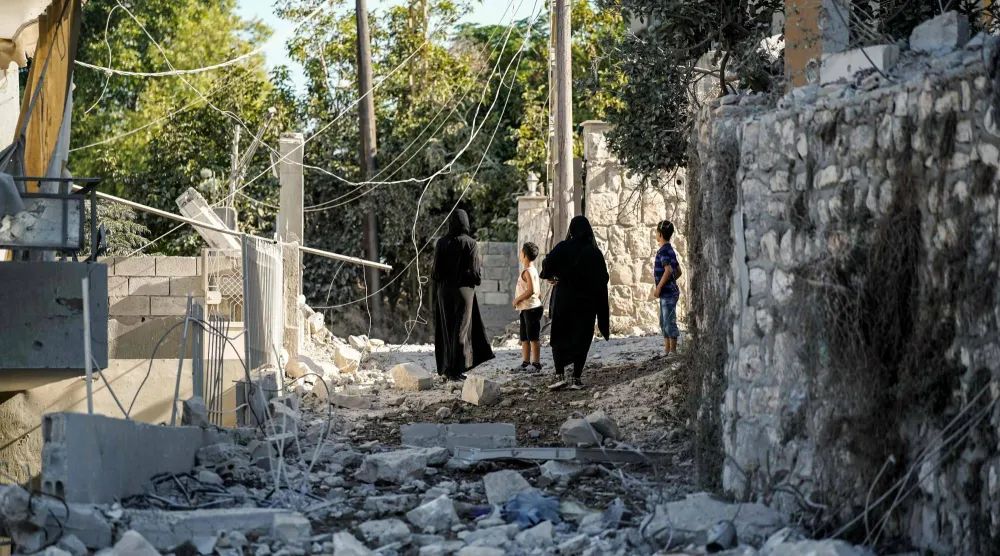سكان يتفقدون الدمار في صباح اليوم التالي لغارة جوية ليلية شنها الجيش الإسرائيلي واستهدفت قرية ميفدون بجنوب لبنان (أ.ف.ب)