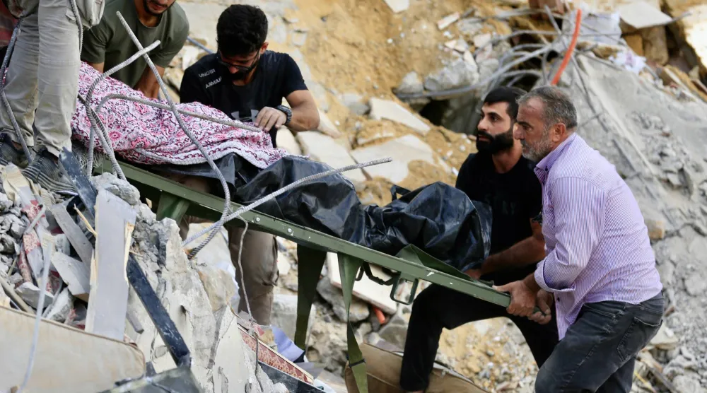سكان محليون ينقلون جثة ضحية قتلت في غارة إسرائيلية استهدفت منزلاً في بلدة عربصاليم جنوب لبنان (إ.ب.أ)