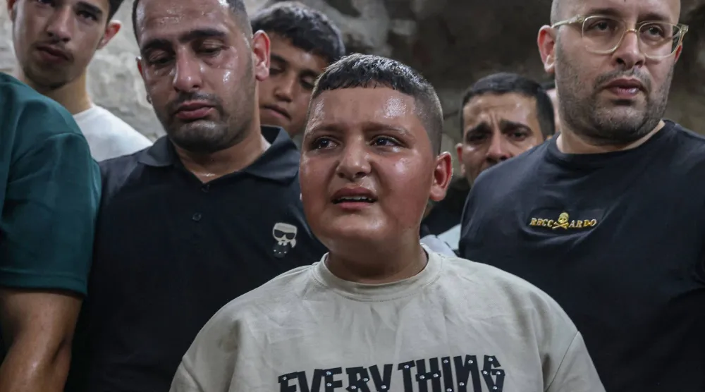 فتى فلسطيني يبكي يوم الاثنين خلال تشييع طالب طب الأسنان عمر طوباسي (20 عاماً) بعد مقتله برصاص مستوطنين إسرائيليين في قرية غرب مدينة نابلس بالضفة الغربية المحتلة (أ.ف.ب)