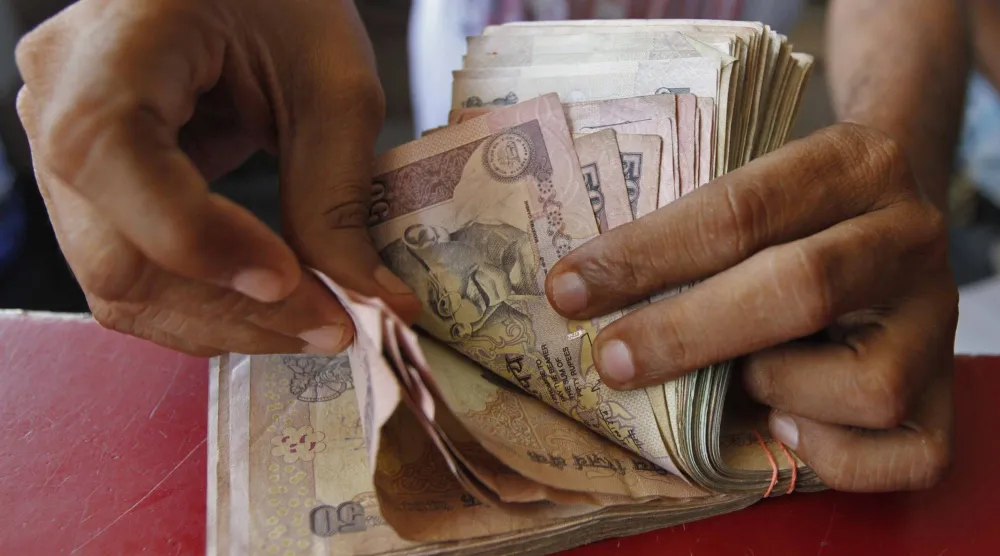 صاحب متجر بقالة يعد أوراق الروبية الهندية في أحمد آباد (رويترز)