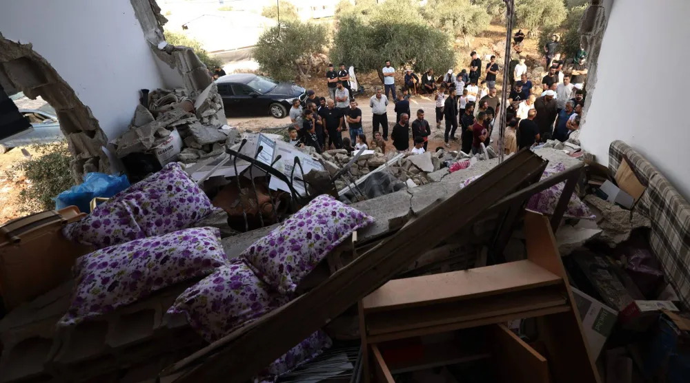 تفقد فلسطينيون منزلاً عائلياً دمره الجيش الإسرائيلي عقب عملية عسكرية بعد أن تحصن رجل فلسطيني داخل المنزل في قرية عقربة بالضفة الغربية المحتلة - جنوب مدينة نابلس (أ.ف.ب)