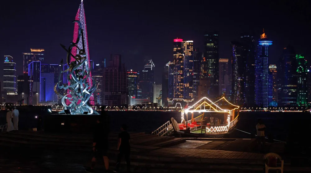 أفراد يسيرون على طول كورنيش الدوحة في مواجهة أفق المباني الشاهقة المضاءة يوم 4 سبتمبر (أ.ف.ب)