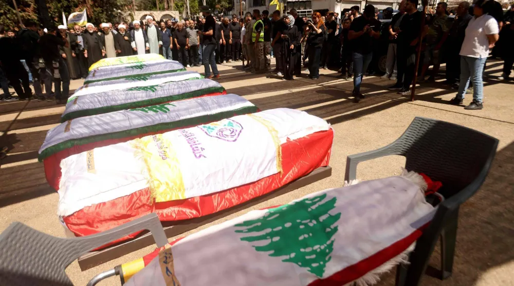 نعوش ملفوفة بالعلم اللبناني خلال تشييع 12 شخصاً قتلوا بغارة إسرائيلية في بلدة كفر رمان بجنوب لبنان الاثنين بينهم مقاتلين اثنين في «حزب الله» (أ.ف.ب)