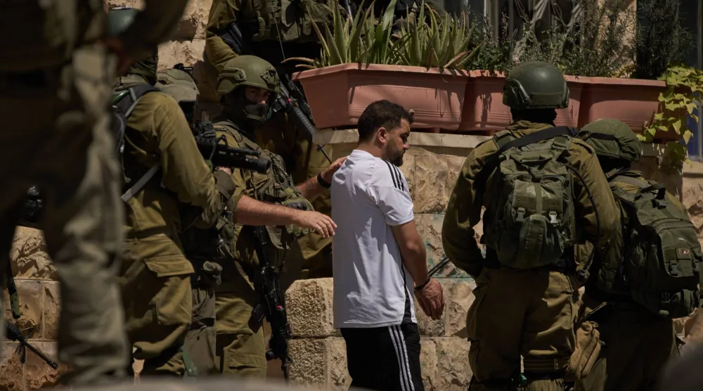 عناصر من القوات الإسرائيلية تعتقل فلسطينياً في أحد شوارع بلدة عناتا بالضفة الغربية المحتلة الثلاثاء (أ.ب)