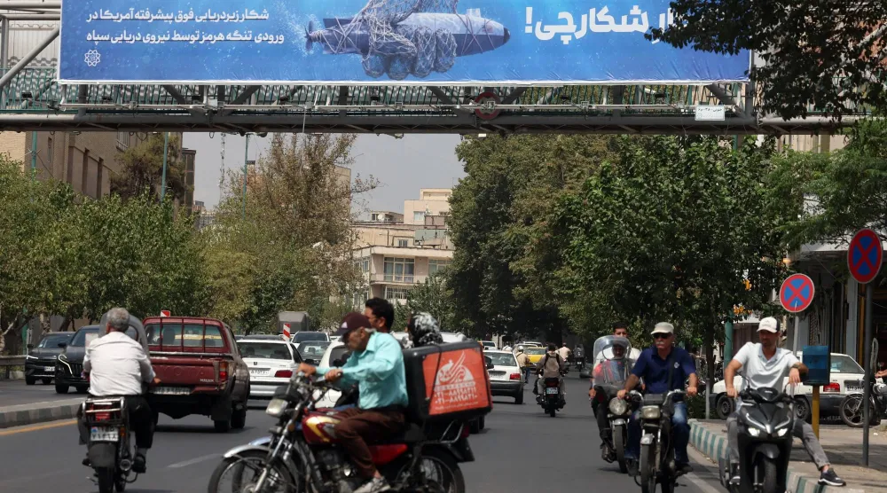 إيرانيون يمرون أمام لوحة دعائية في طهران تُظهر مسيّرة أميركية تحت الماء قال «الحرس الثوري» إنه استولى عليها وتحمل عبارة «صيد الصياد» 9 سبتمبر 2026 (إ.ب.أ)
