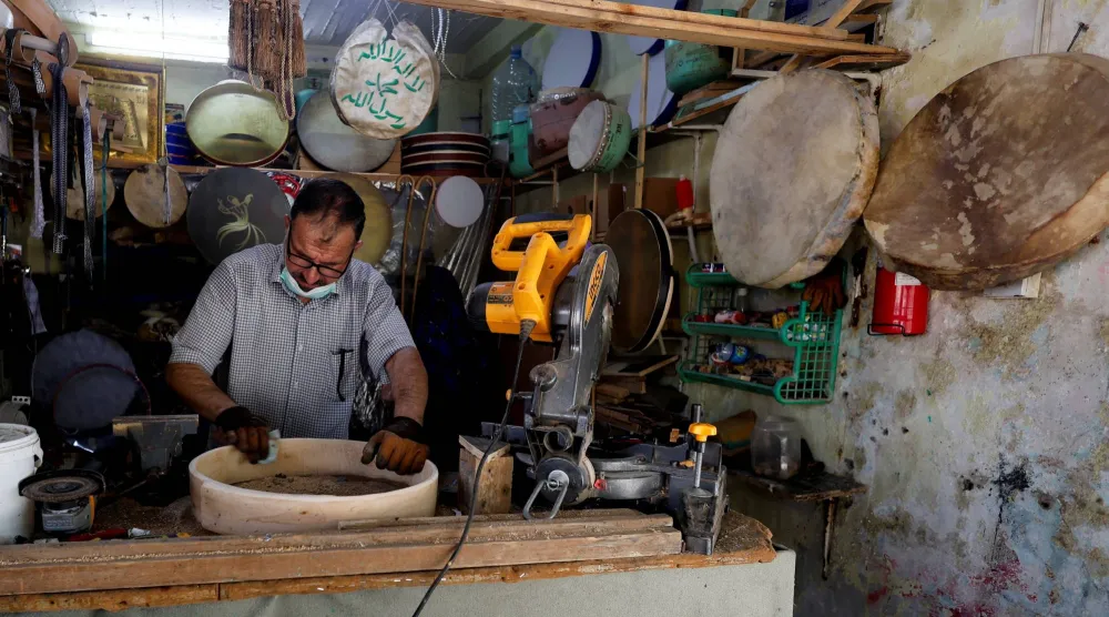حرفي تقليدي لطبل الدف يعمل في ورشته بمدينة الموصل، العراق (رويترز)