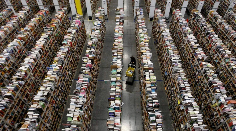 عامل يجمع طلبات لتسليمها من أرضية المستودع بمركز توزيع تابع لشركة «أمازون» في فينيكس بأريزونا (أرشيفية - رويترز)