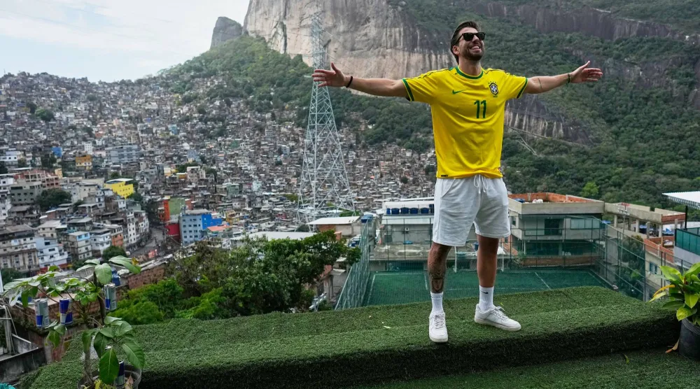A tourist wearing a jersey in Brazilian colors poses for photos on a terrace at the Rocinha favela in Rio de Janeiro, on Sept. 2, 2026. (AP Photo/Silvia Izquierdo)
