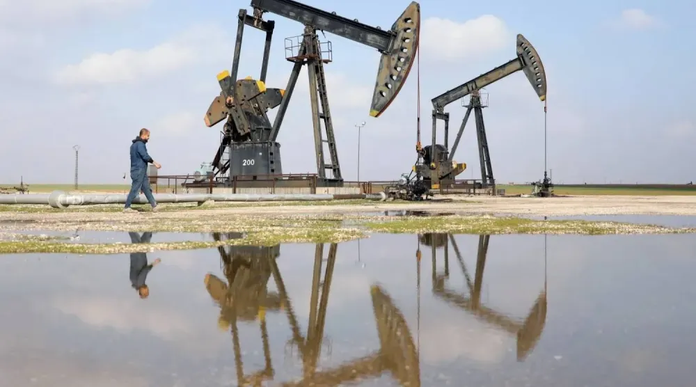 رجل يمر بجوار مضخات نفط في مدينة رميلان الغنية بالنفط في سوريا (رويترز)