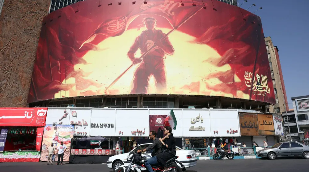 Iranians drive past a political billboard at the Valiasr square in central Tehran, Iran, 13 September 2026.  EPA/ABEDIN TAHERKENAREH 