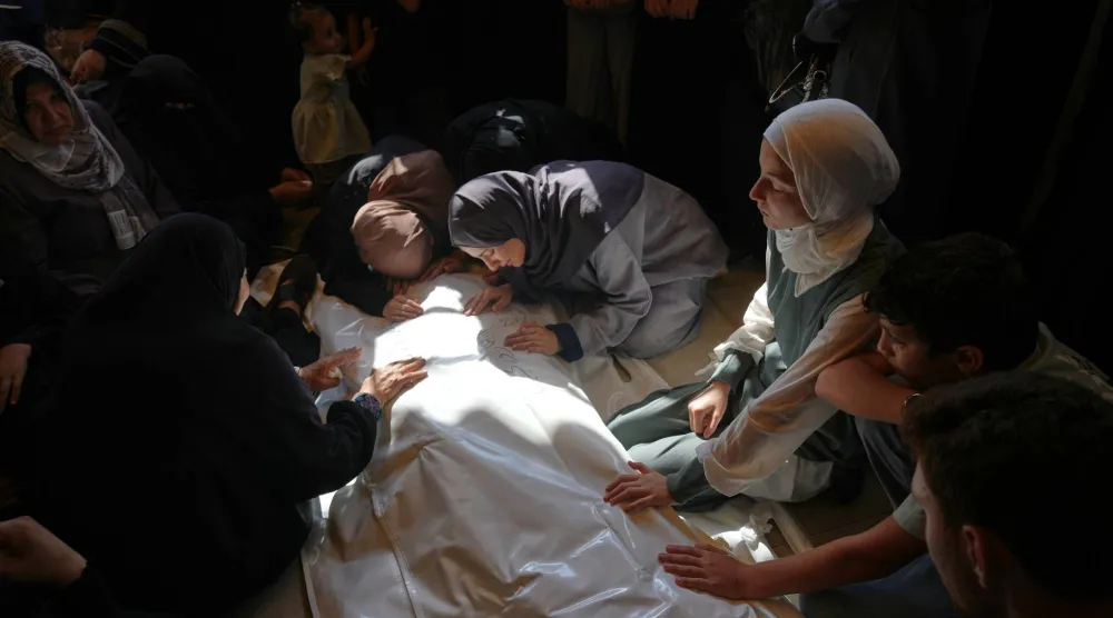 فلسطينيات يبكين محمد اليازوري الذي قُتل بغارة جوية إسرائيلية الخميس الماضي قبيل تشييع جثمانه في خان يونس جنوب غزة (أ.ب)