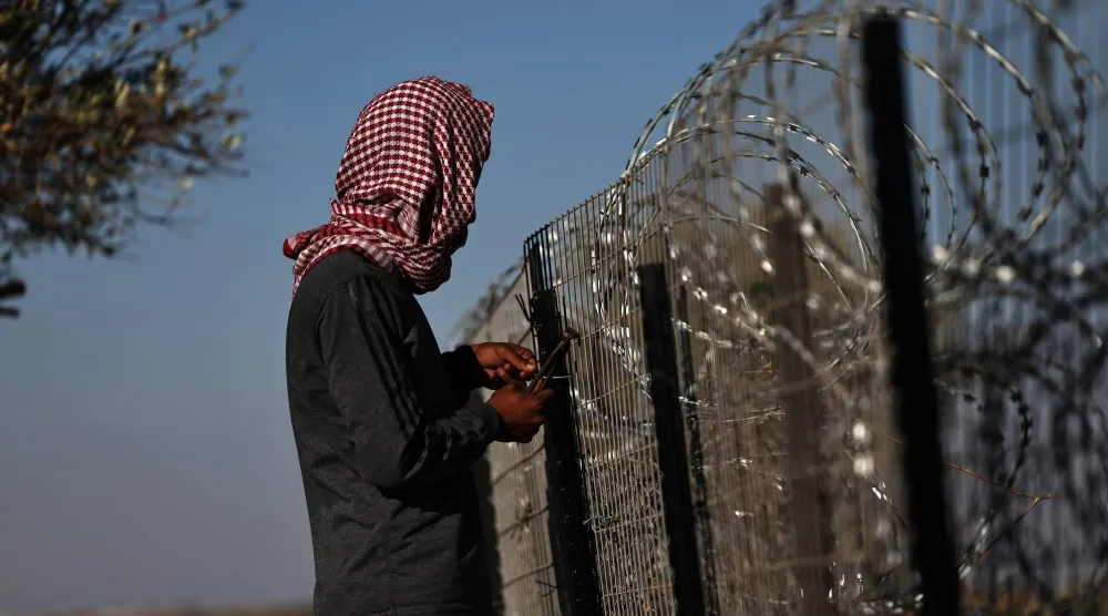 فلسطيني أمام أسلاك شائكة تحيط بمنزله لحمايته من هجمات المستوطنين في قرية الطيبة بالضفة الغربية يوم 9 سبتمبر 2026 (إ.ب.أ)