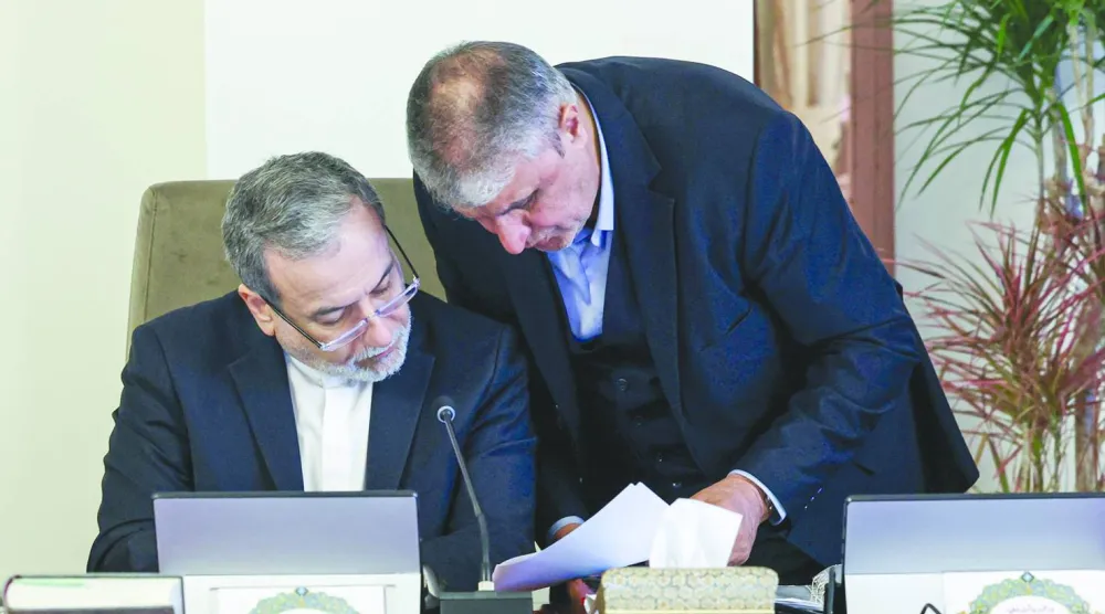 رئيس المنظمة الإيرانية للطاقة الذرية محمد إسلامي ووزير الخارجية عباس عراقجي يراجعان مسودة على هامش اجتماع للحكومة (الرئاسة الإيرانية)