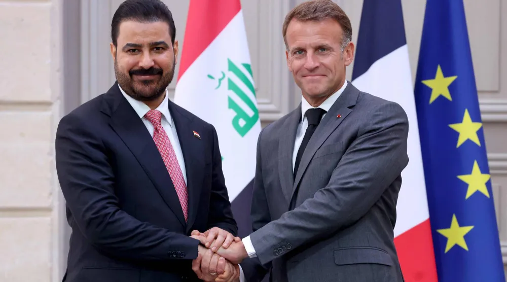 مصافحة بين الرئيس ماكرون ورئيس الوزراء العراقي علي الزيدي عقب مراسم التوقيع (أ.ف.ب)