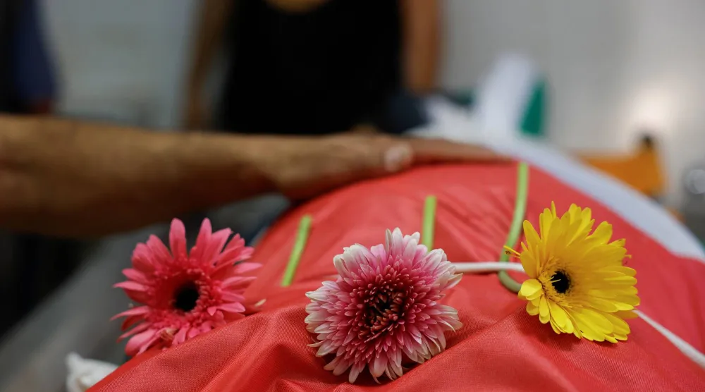 وُضعت زهور على جثمان رجل فلسطيني يبلغ من العمر 54 عاماً، قُتل على يد القوات الإسرائيلية خلال مداهمة، بينما كان المشيعون ينعونه في مستشفى بمدينة رام الله في الضفة الغربية (رويترز)