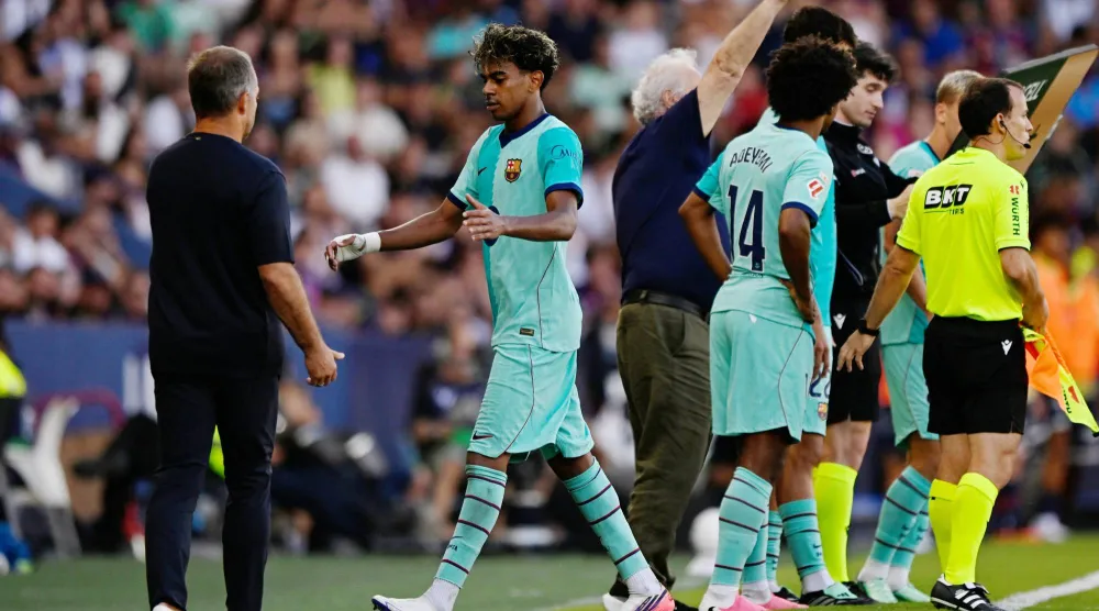 هانزي فليك مدرب برشلونة يصافح لاعبه لامين يامال (رويترز)