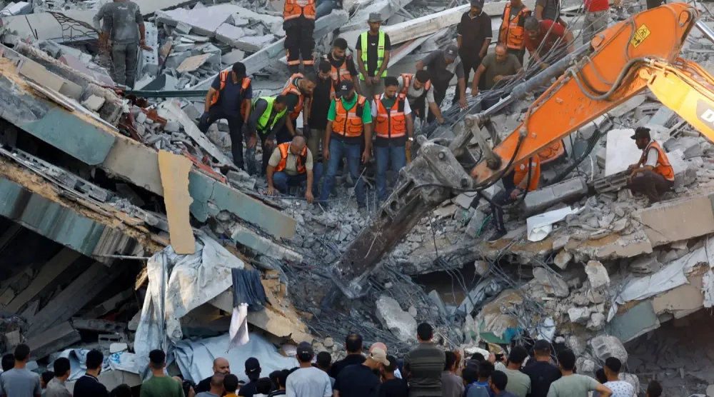 İnsanlar, bugün Gazze kentinde çöken binanın enkazı altında mahsur kalanları kurtarmaya çalışan sivil savunma ekiplerinin çevresinde toplanıyor (Reuters)