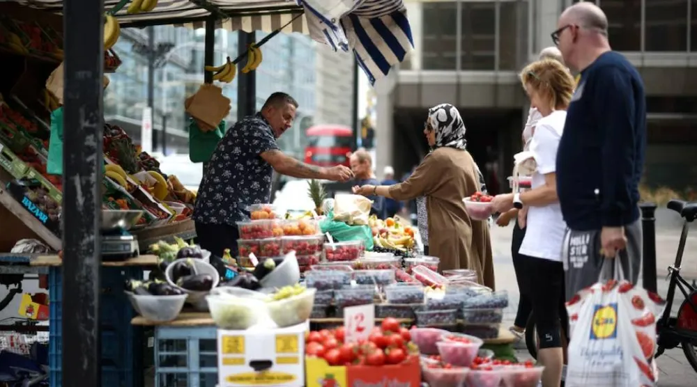 متسوّق يشتري الفواكه والخضراوات من إحدى بسطات البيع في وسط لندن ببريطانيا (رويترز)