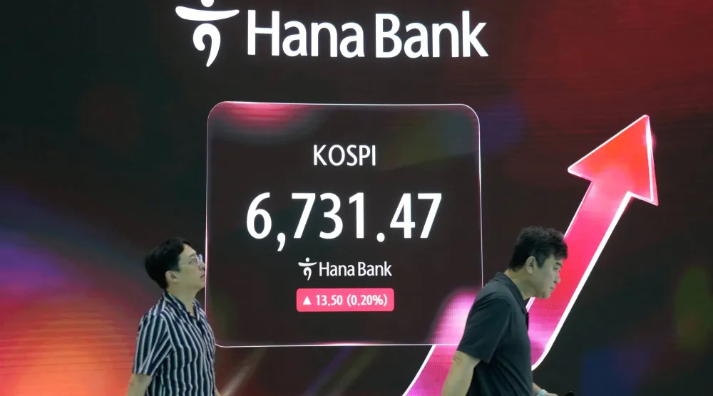متداولون يمرون أمام شاشة تعرض مؤشر «كوسبي» في غرفة تداول العملات الأجنبية بمقر بنك «هانا» في سيول (أ.ب)