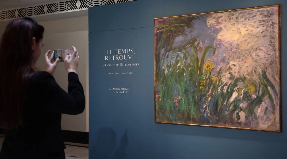 A visitor takes a picture of the painting "Iris, 1924-1925" by French painter Claude Monet (1840-1926) during the presentation of 28 art works from the Schlumberger Collection ahead of the auction at Sotheby's auction house in Paris, France, September 17, 2026. REUTERS/Abdul Saboor