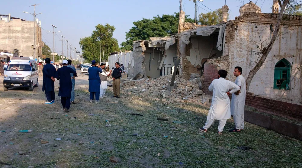 أشخاص يقفون بالقرب من سيارة إسعاف وجزء متضرر من مركز للشرطة عقب هجوم انتحاري في كوهات... الجمعة (رويترز)