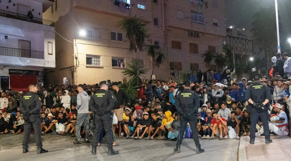 عناصر الشرطة خلال تأمين عملية نقل المهاجرين من شواطئ سبتة إلى مخيم في منطقة الميناء (رويترز)