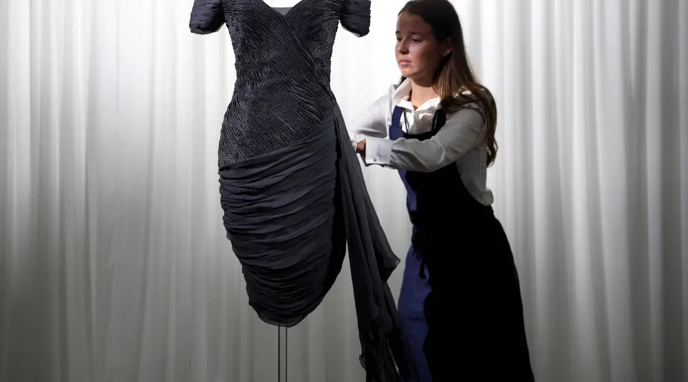 A Sotheby’s employee adjusts Princess Diana's "Revenge Dress" by Greek designer Christina Stambolian in London, Britain, September 18, 2026. REUTERS/Toby Melville